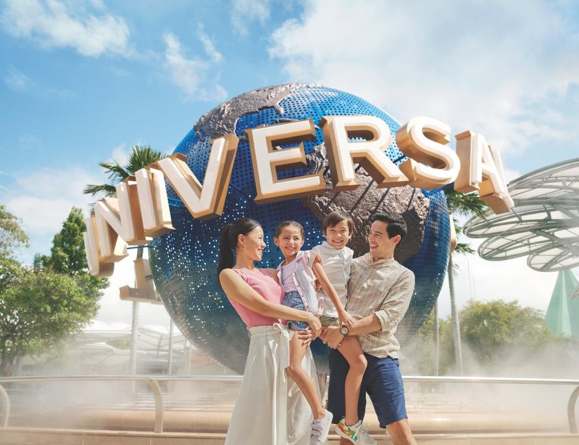 ครอบครัวยืนถ่ายรูปหน้าแลนด์มาร์กลูกโลก Universal ที่ทางเข้า Universal Studios Singapore ในสิงคโปร์