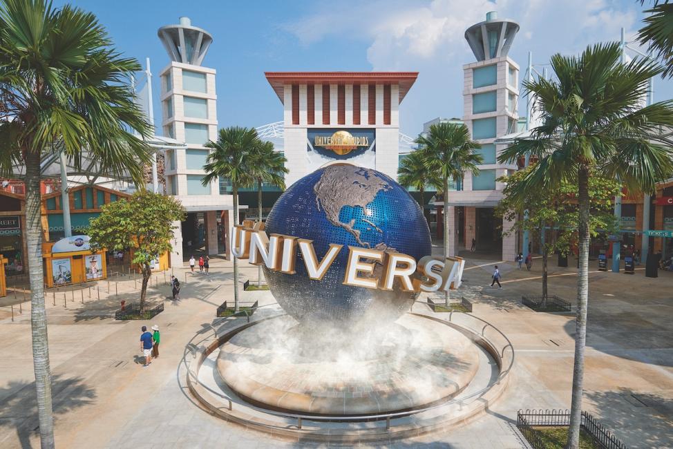 ภาพทางเข้า Universal Studios Singapore พร้อมลูกโลก Universal ขนาดใหญ่ด้านหน้า รายล้อมด้วยต้นปาล์ม ในสิงคโปร์